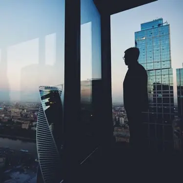 Silhouette of a person looking through a high-rise window